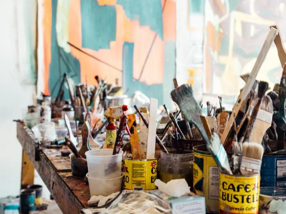 An artist's studio crowded with brushes, paint pots and canvases