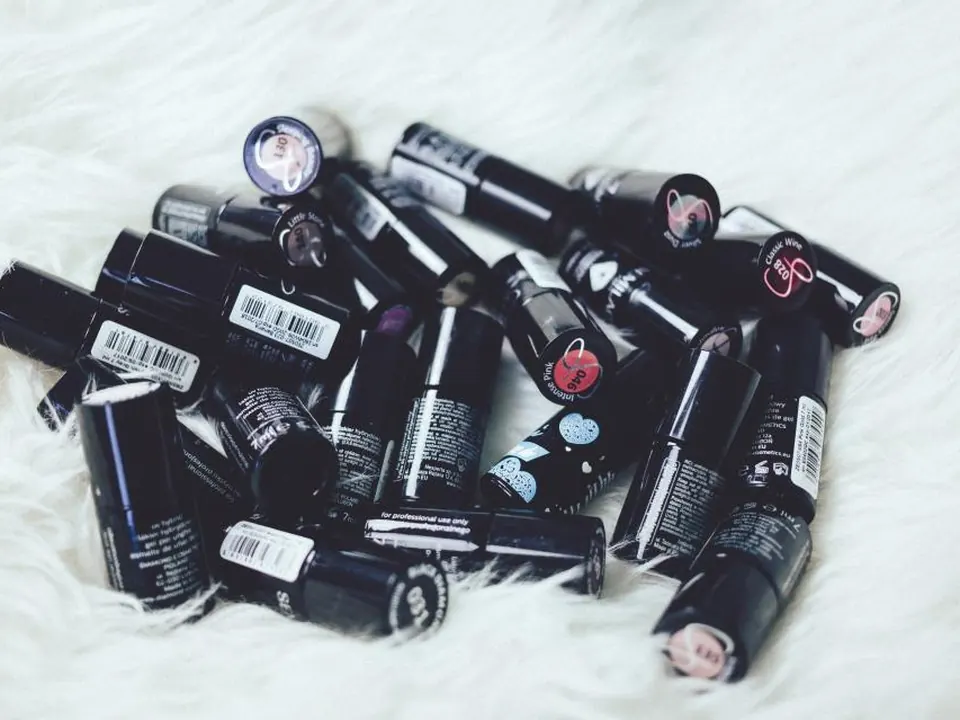 A pile of black lipstick tubes on white fur