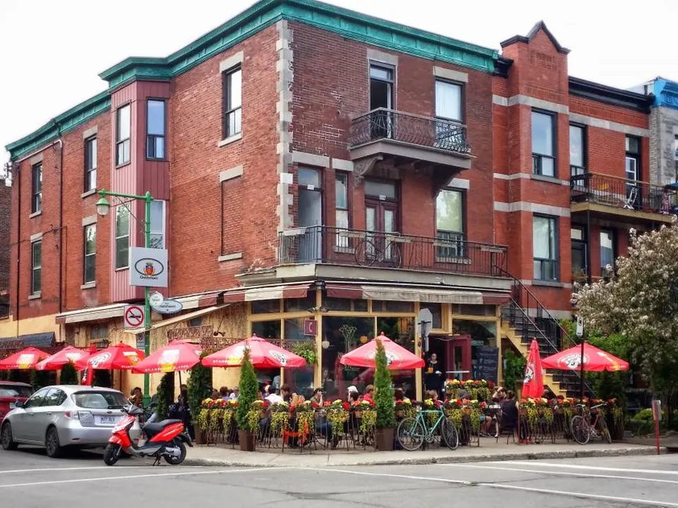 Red-brick corner building with a busy restaurant patio