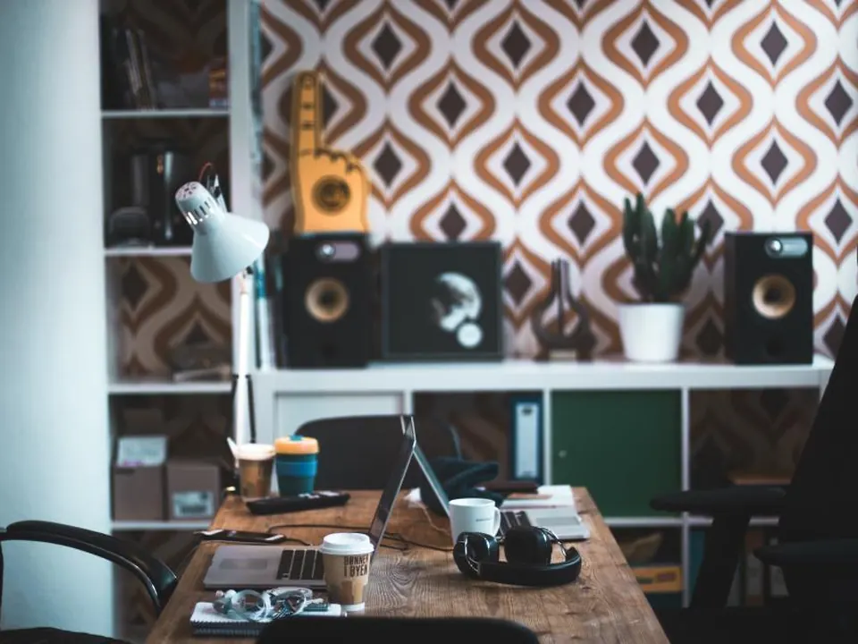 Desk with a lamp in front of a bold patterned wallpaper