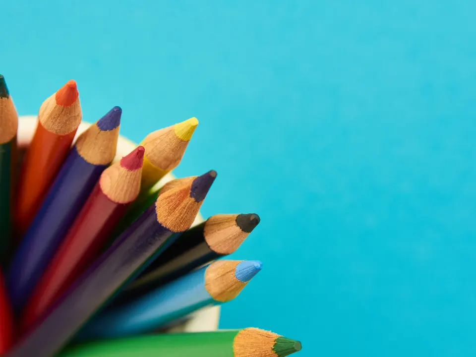Fan of colored pencils on a turquoise background