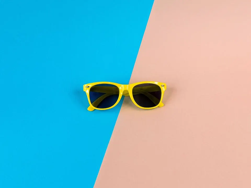 Yellow sunglasses on a split blue and pink background